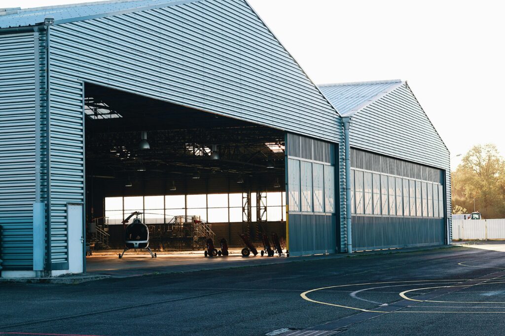 A modern industrial hangar exterior with a helicopter visible, offering spacious interior views.