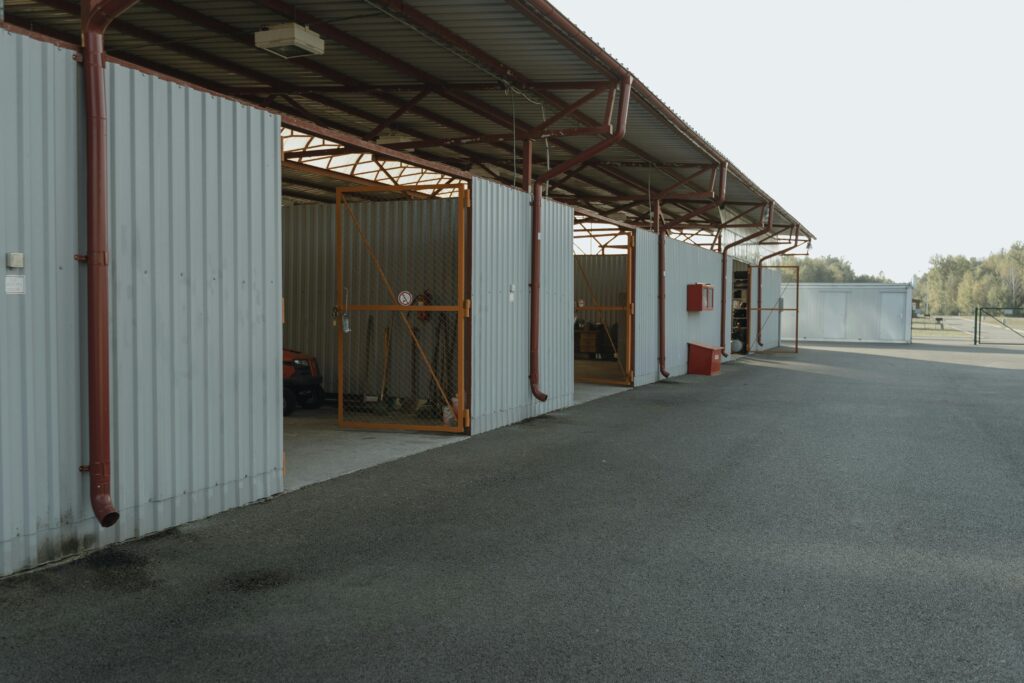 An empty industrial garage with open doors and a view of the spacious outdoor area.