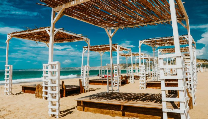 Relaxing beachfront view with wooden loungers and straw pergolas in a tropical resort.